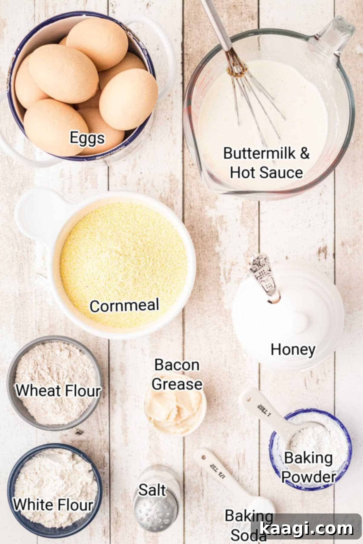 Fiery Cajun Cornbread 3 All the fresh ingredients laid out on a wooden surface for making Cajun cornbread, including cornmeal, flours, eggs, buttermilk, honey, and bacon grease.