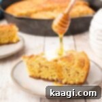Fiery Cajun Cornbread 5 Slice of cornbread with honey drizzled on top, ready to be served from a skillet.