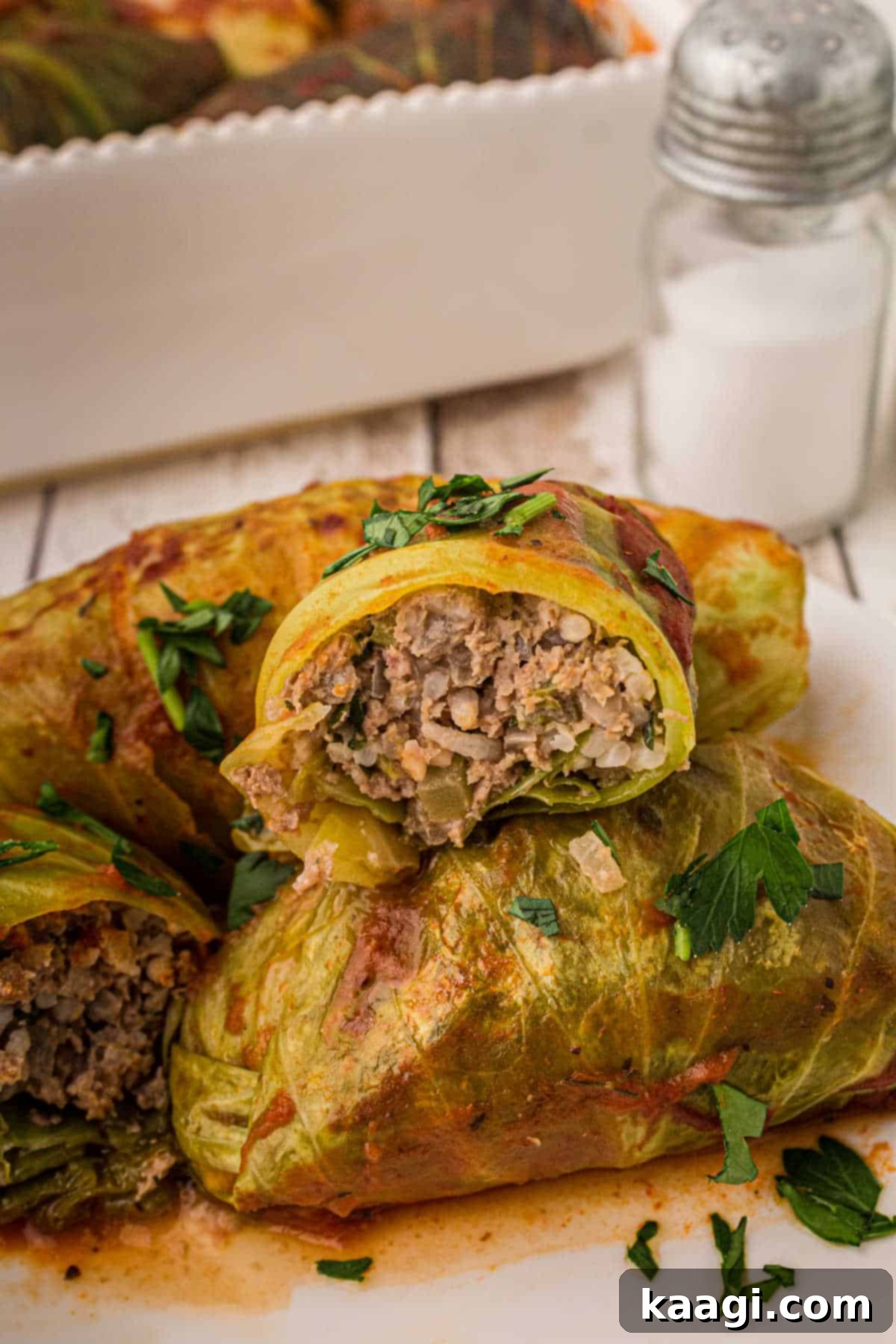 Old-World Cabbage Rolls 5 A beautifully presented stack of golden-brown stuffed Cabbage Rolls, with one roll expertly sliced open to showcase the perfectly cooked, aromatic meat and rice filling nestled within the tender cabbage leaves.