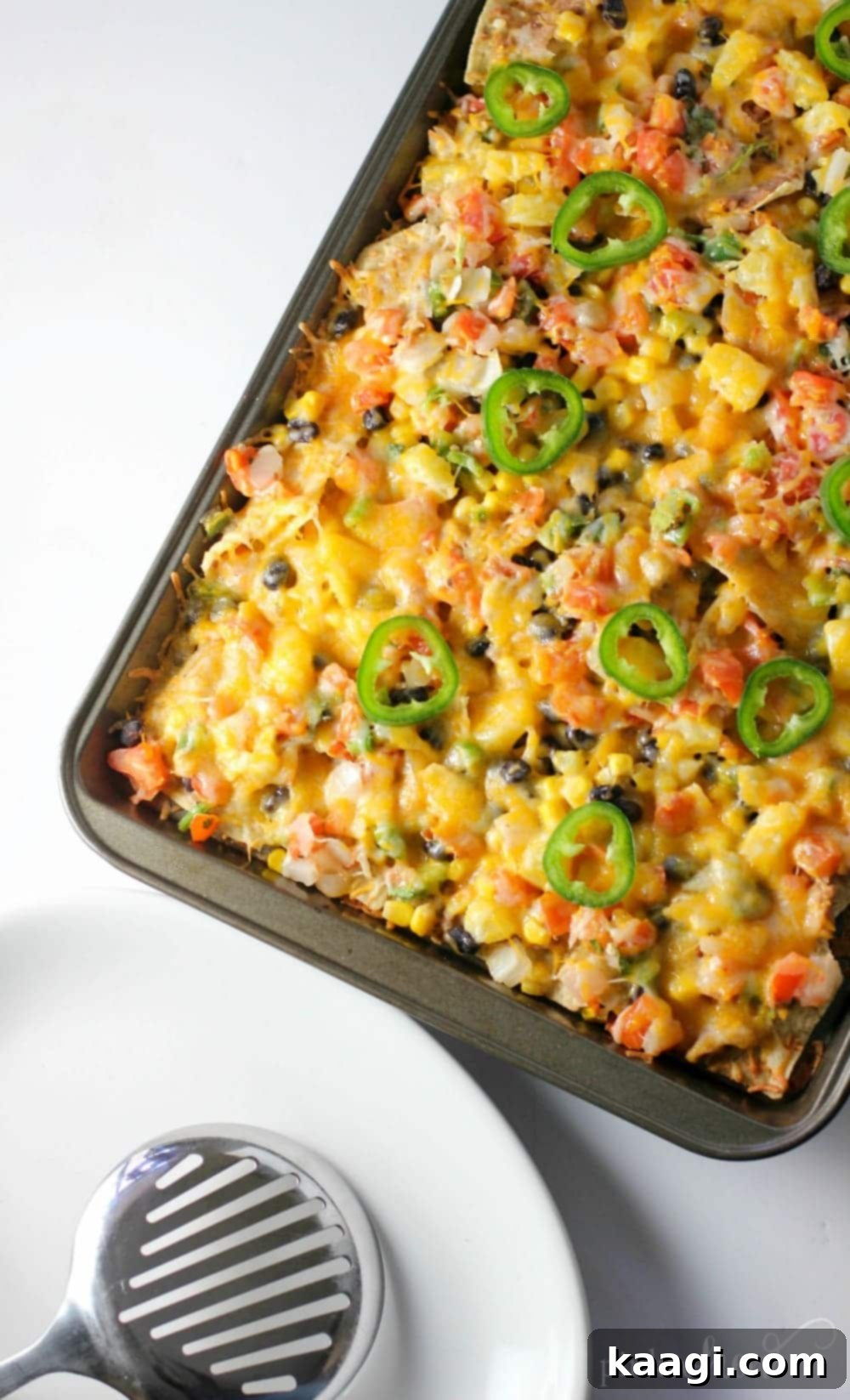 Ultimate Game Day Chicken Nachos, featuring chicken, cheese, black beans, corn, pico de gallo, and pineapple chunks.