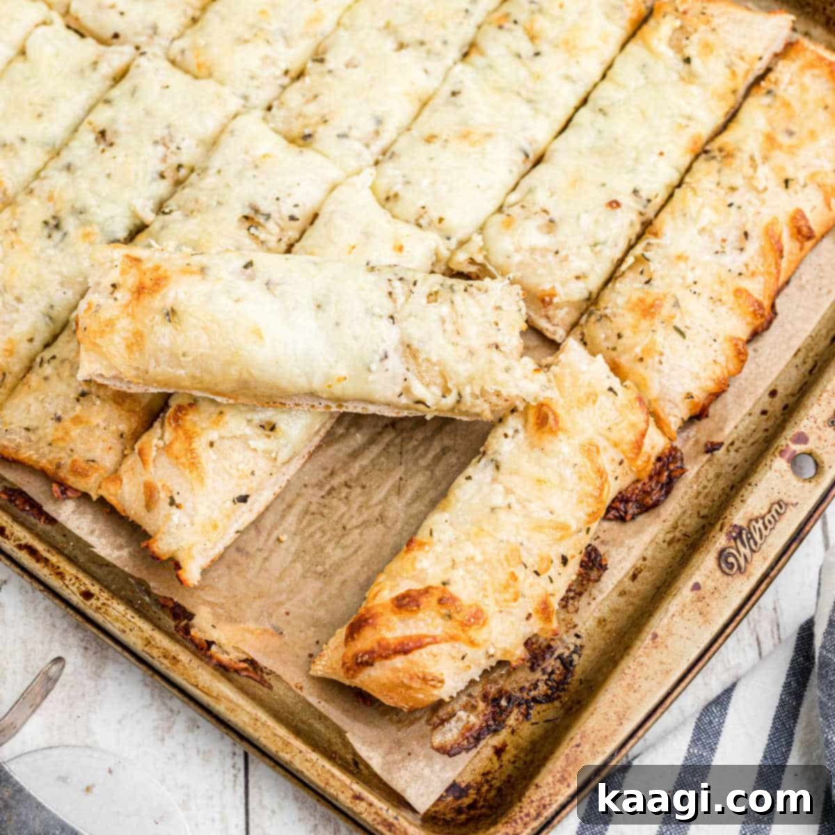Square shot of an Italian cheese bread with one piece already removed, showing the cheesy, golden interior.