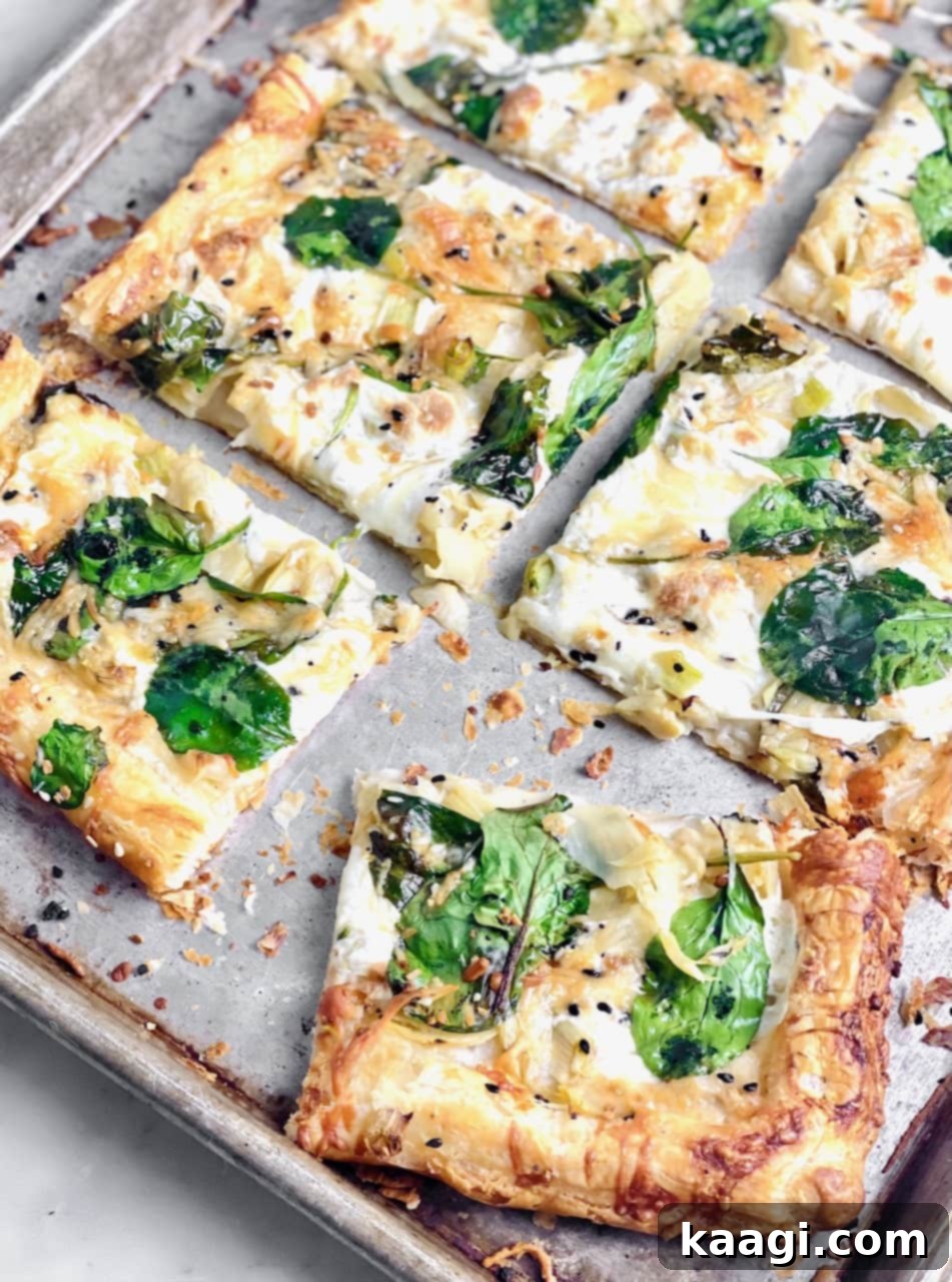 Creamy Spinach Alfredo Pizza with fresh spinach, artichokes, and a cheesy puff pastry crust.