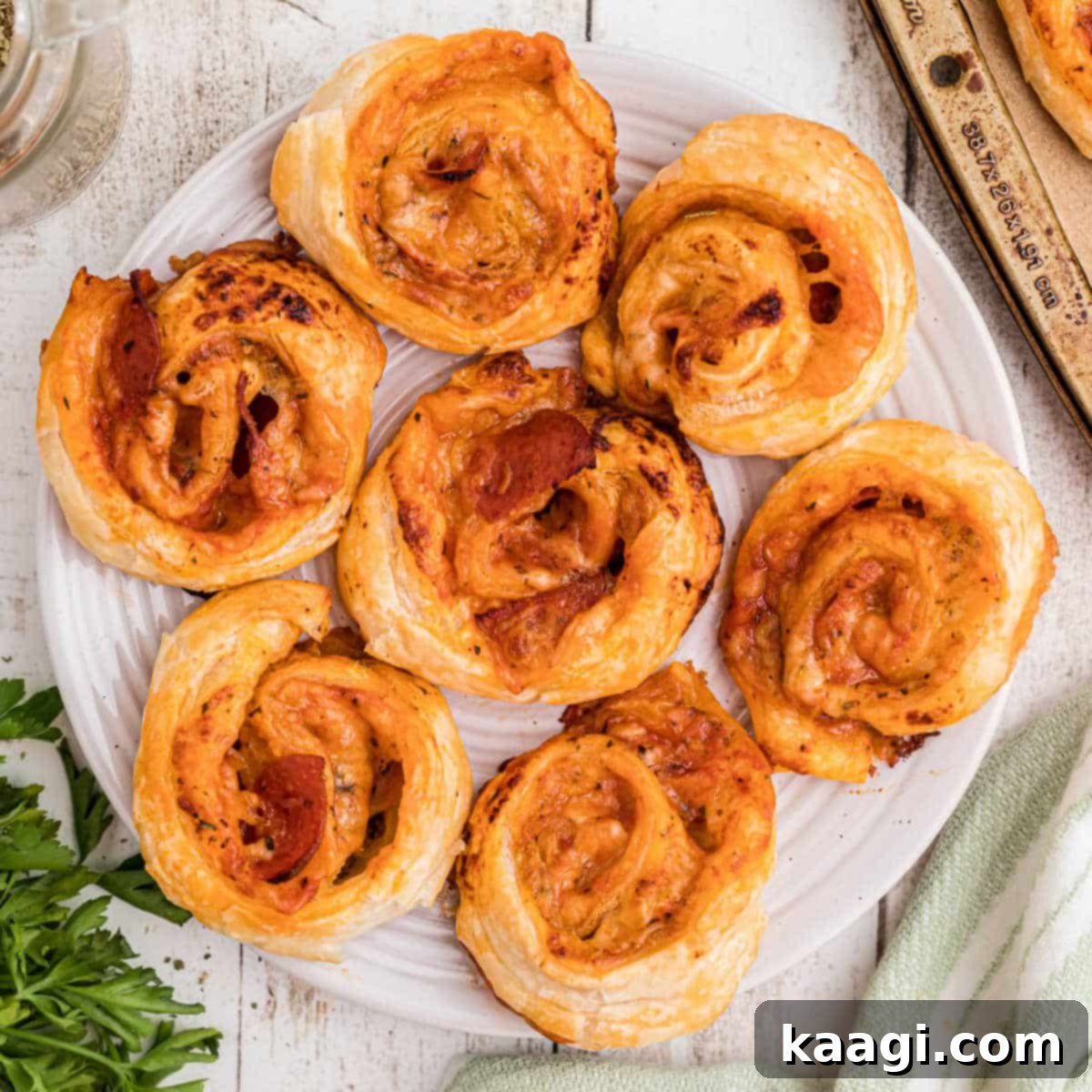 A close-up overhead shot of a plate full of puff pastry pizza pinwheels, perfectly flaky and delicious.