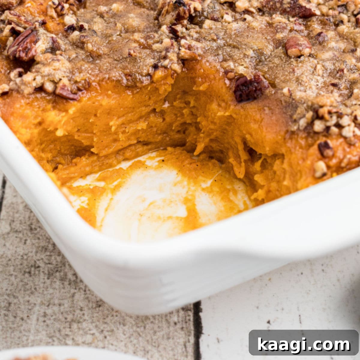 Close-up of a corner of a dish of Cracker Barrel Sweet Potato Casserole, with a scoop missing, revealing the creamy texture.