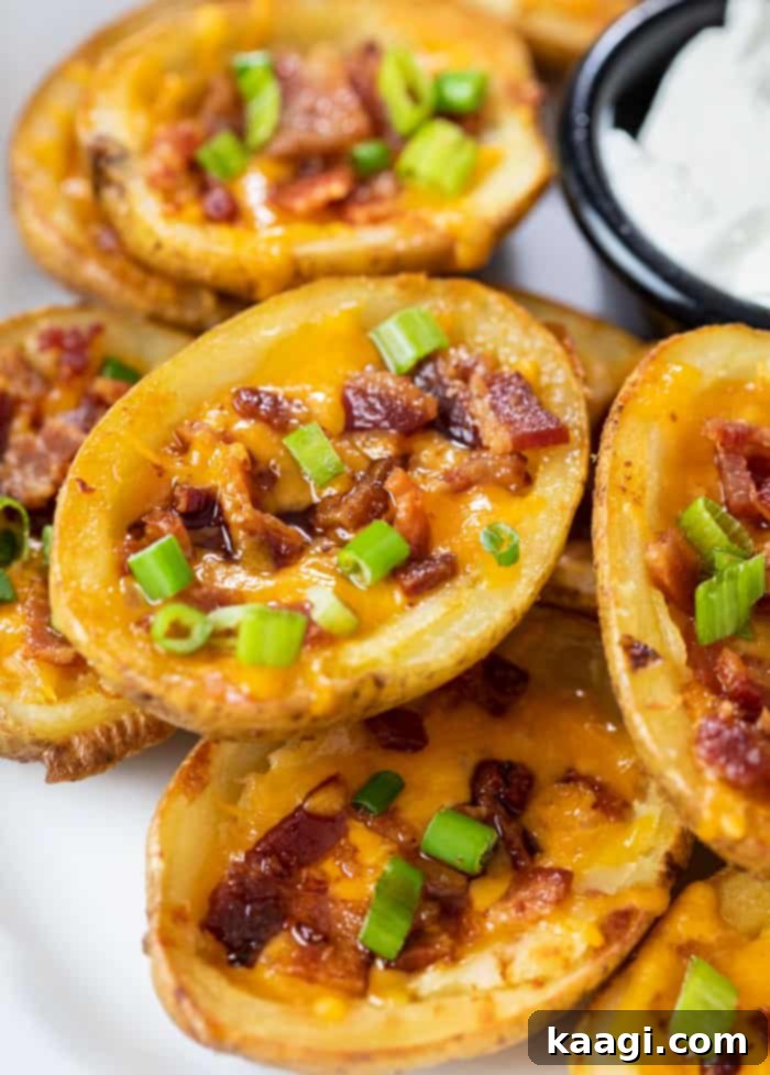Crispy baked Potato Skins, topped with cheddar cheese, bacon, green onions, and sour cream, for the ultimate appetizer.