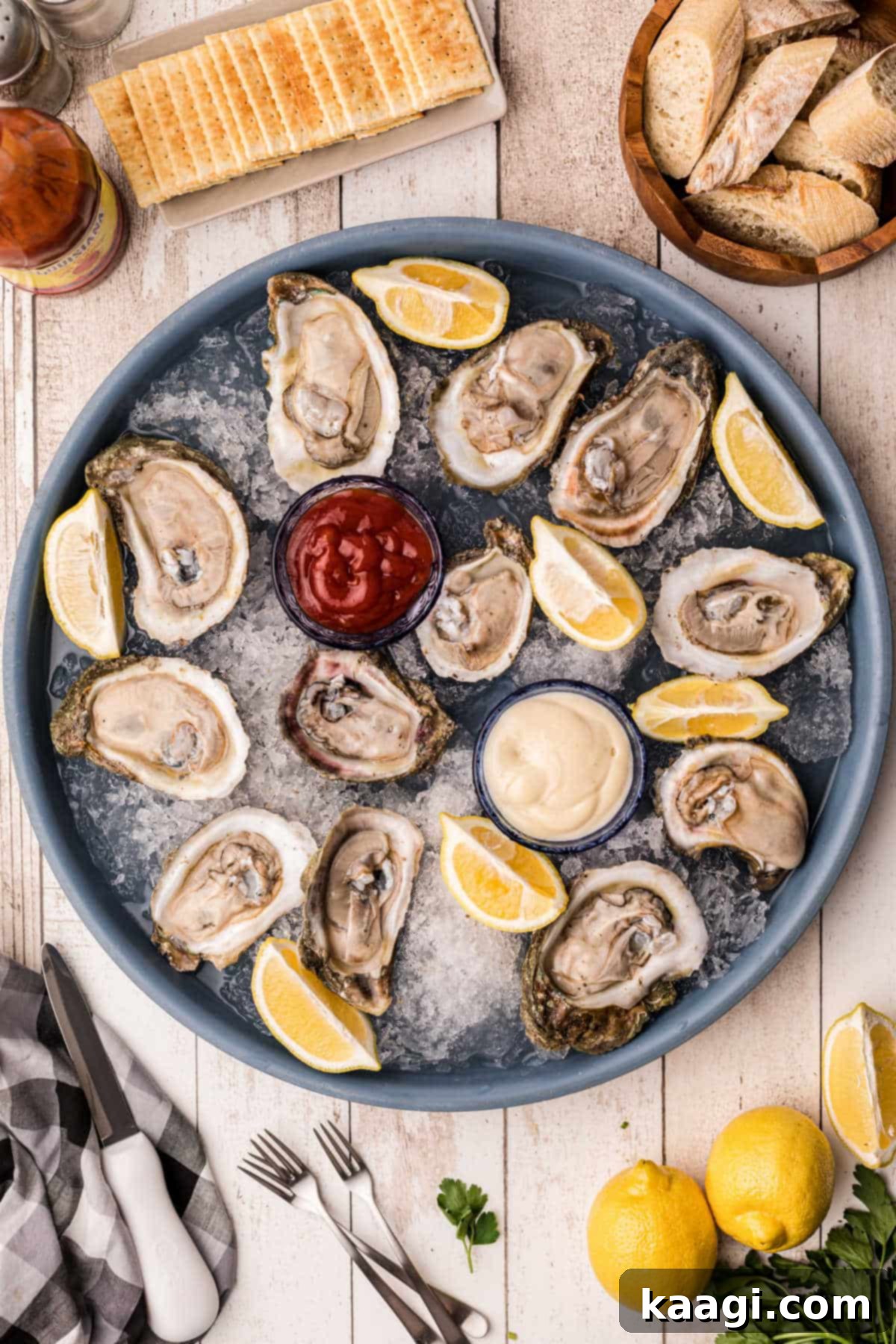 A beautifully arranged platter of raw oysters on ice, garnished with lemon wedges.