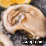 raw oyster on ice with lemon wedge, glistening and ready to eat