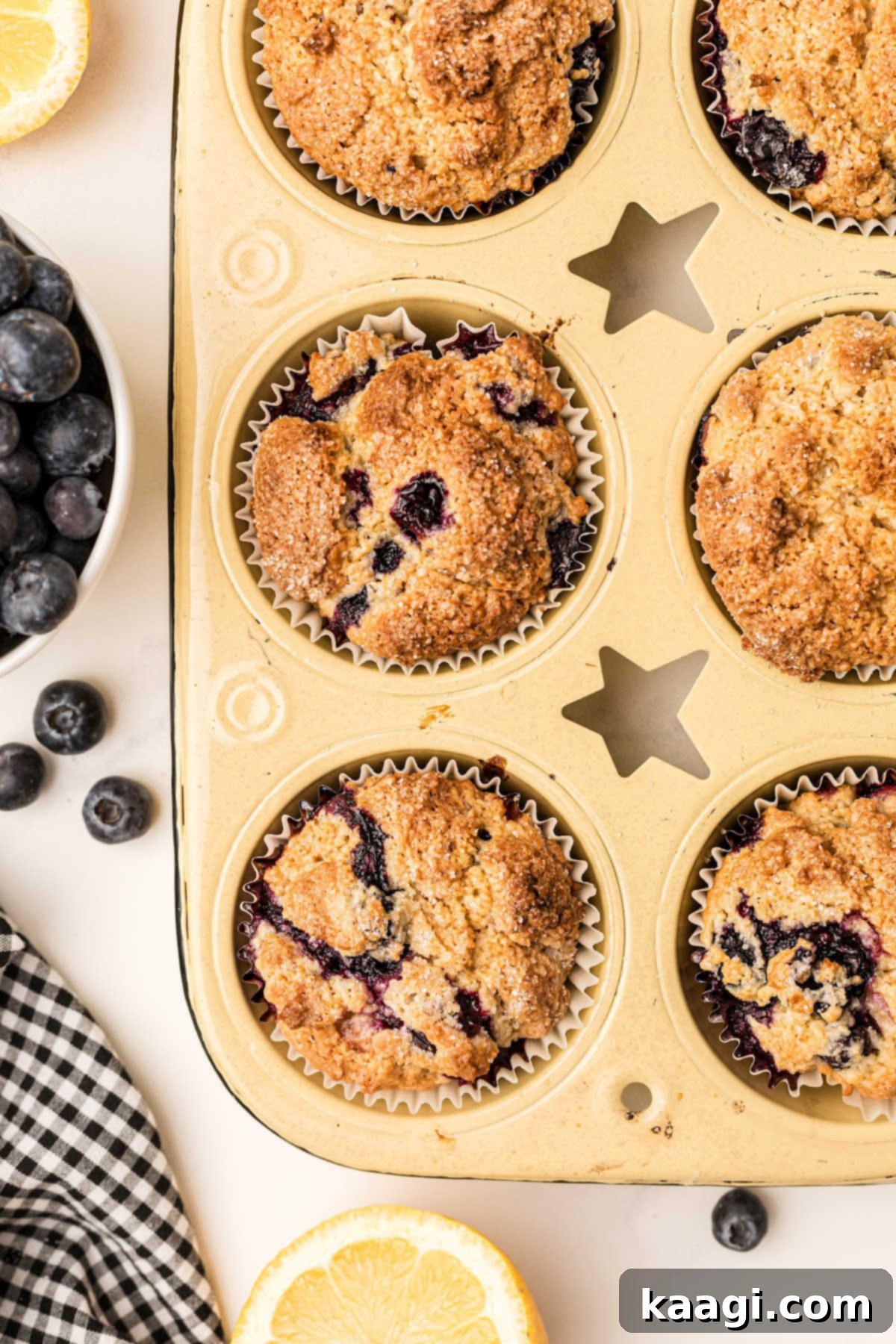 a yellow muffin tin with lemon blueberry muffins cooked in it