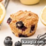 Close up of a lemon blueberry muffin with some lemons on the side.