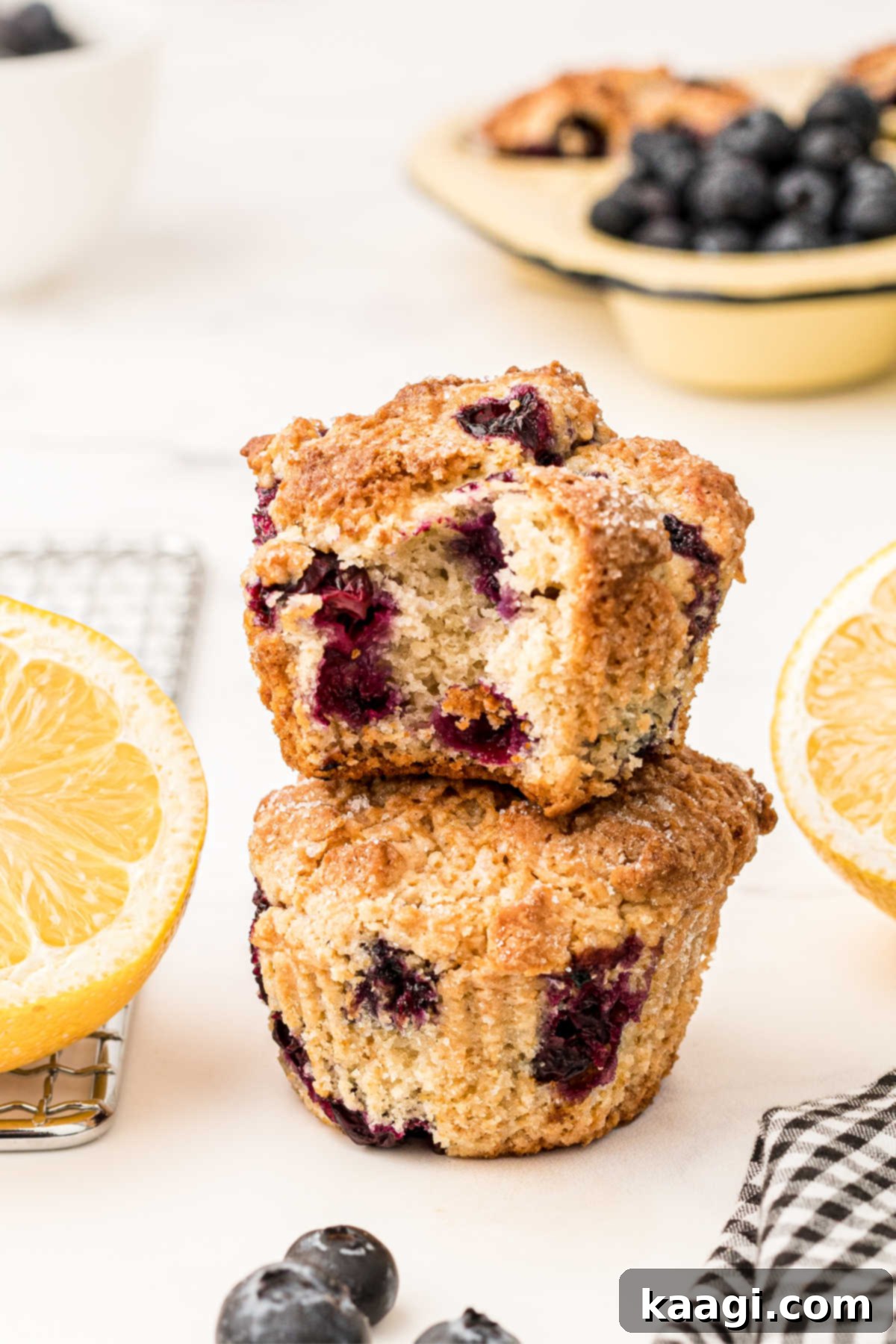 two lemon and blueberry muffins with sour cream stacked with the top one with a bite taken out