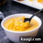 A close-up of a steaming bowl of creamy cheese grits, with a spoon digging into the rich texture.