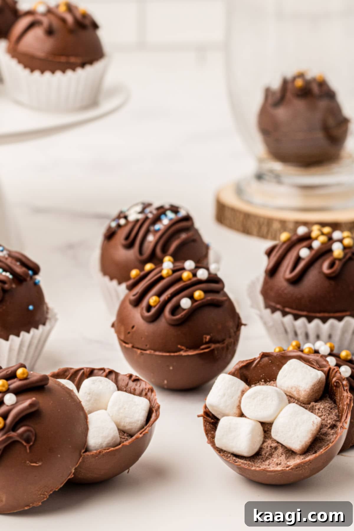 Homemade Hot Chocolate Bomb Magic 2 Delicious hot chocolate bombs, some opened to reveal hot chocolate mix and marshmallows inside, ready to be dropped into a mug.