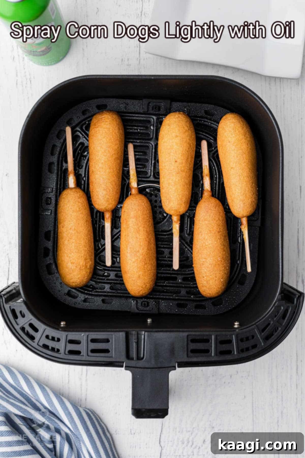 Several frozen corn dogs neatly lined up in a single layer inside the basket of an air fryer, ready to be cooked to crispy perfection.