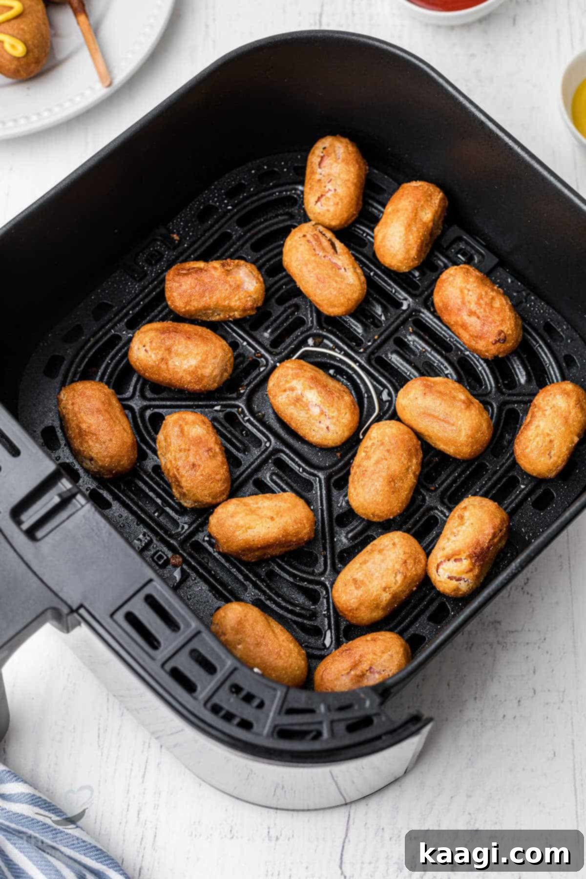 A basket of an air fryer filled with perfectly cooked mini corn dogs, golden and crispy, ready to be served as a delightful snack.