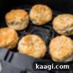 Air fryer basket filled with golden-brown, freshly cooked biscuits, ready to be removed and served.