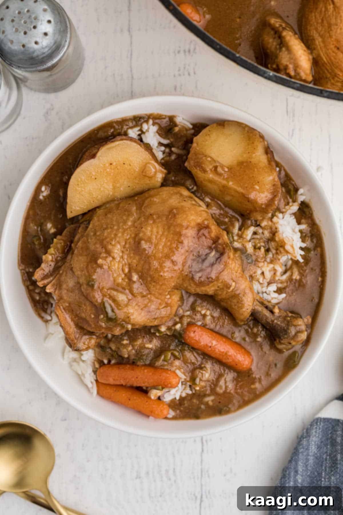 bowl of rice topped with chicken stew, whole leg with carrots and potatoes