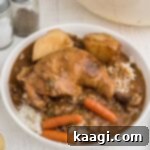 bowl of rice topped with chicken stew, whole leg with carrots and potatoes