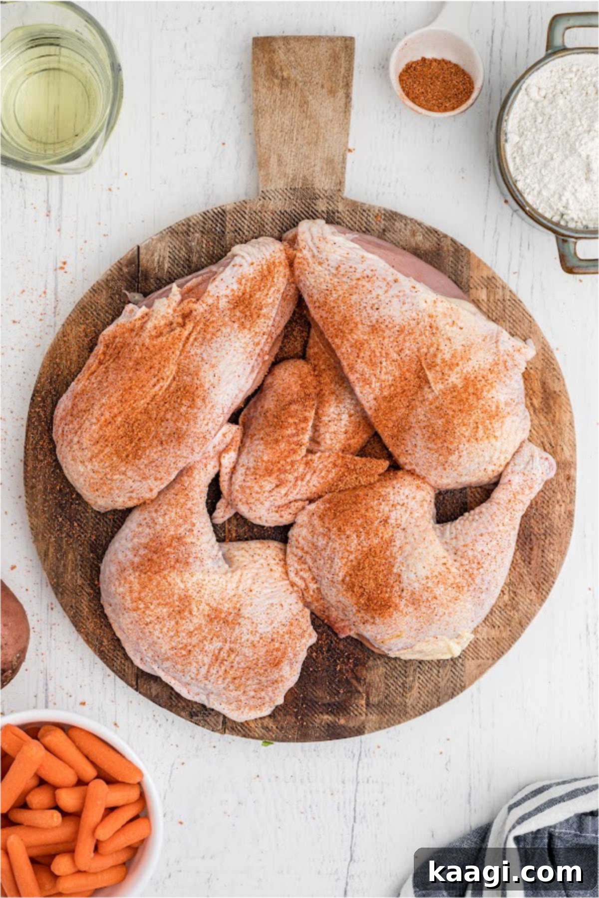 Chicken pieces on a chopping board, covered in seasoning.