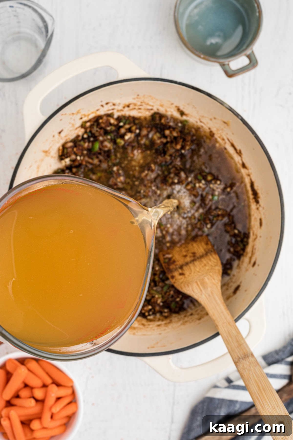 Chicken broth being added to a pot with roux.