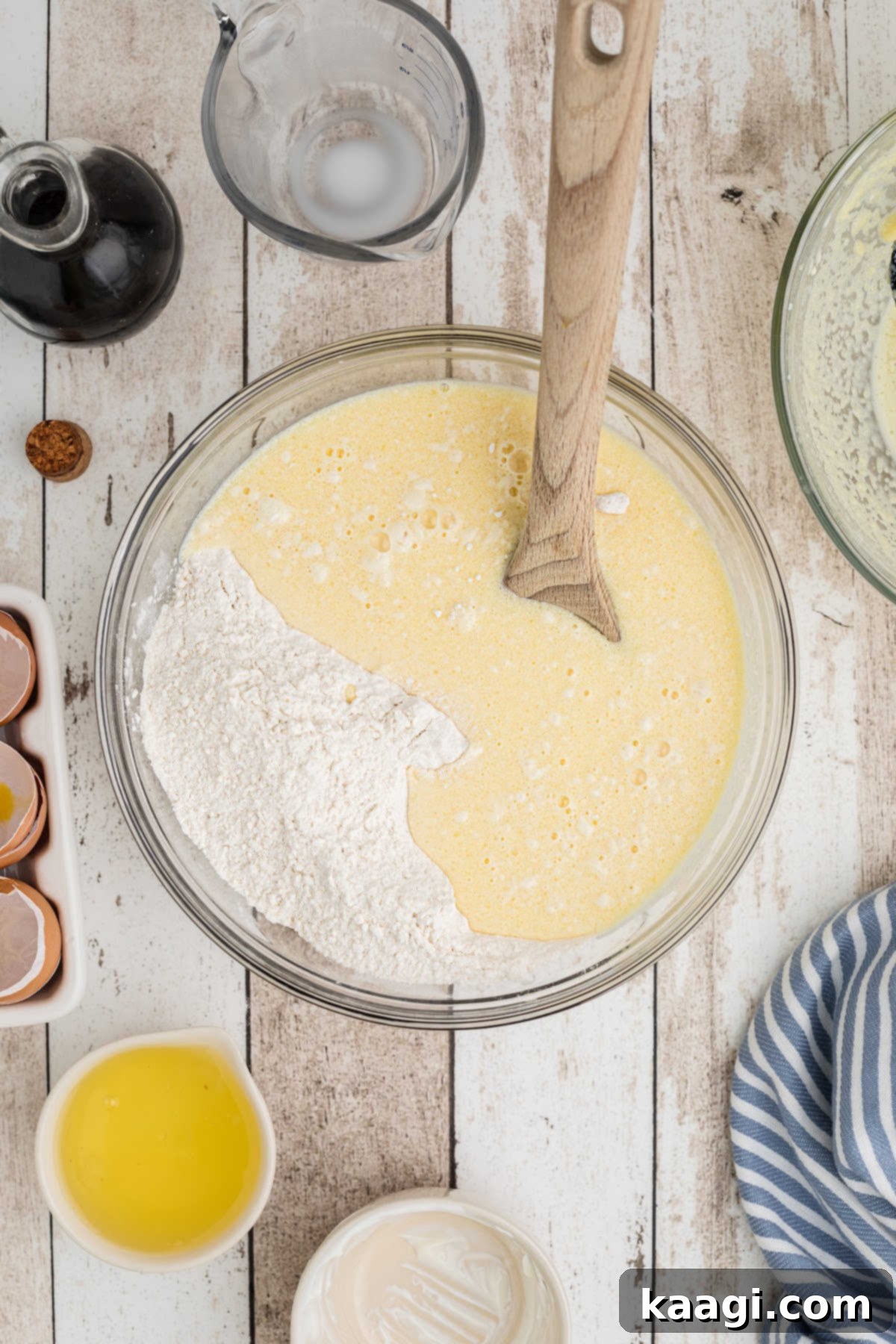 A large mixing bowl with a egg mixture being mixed with a flour mixture.