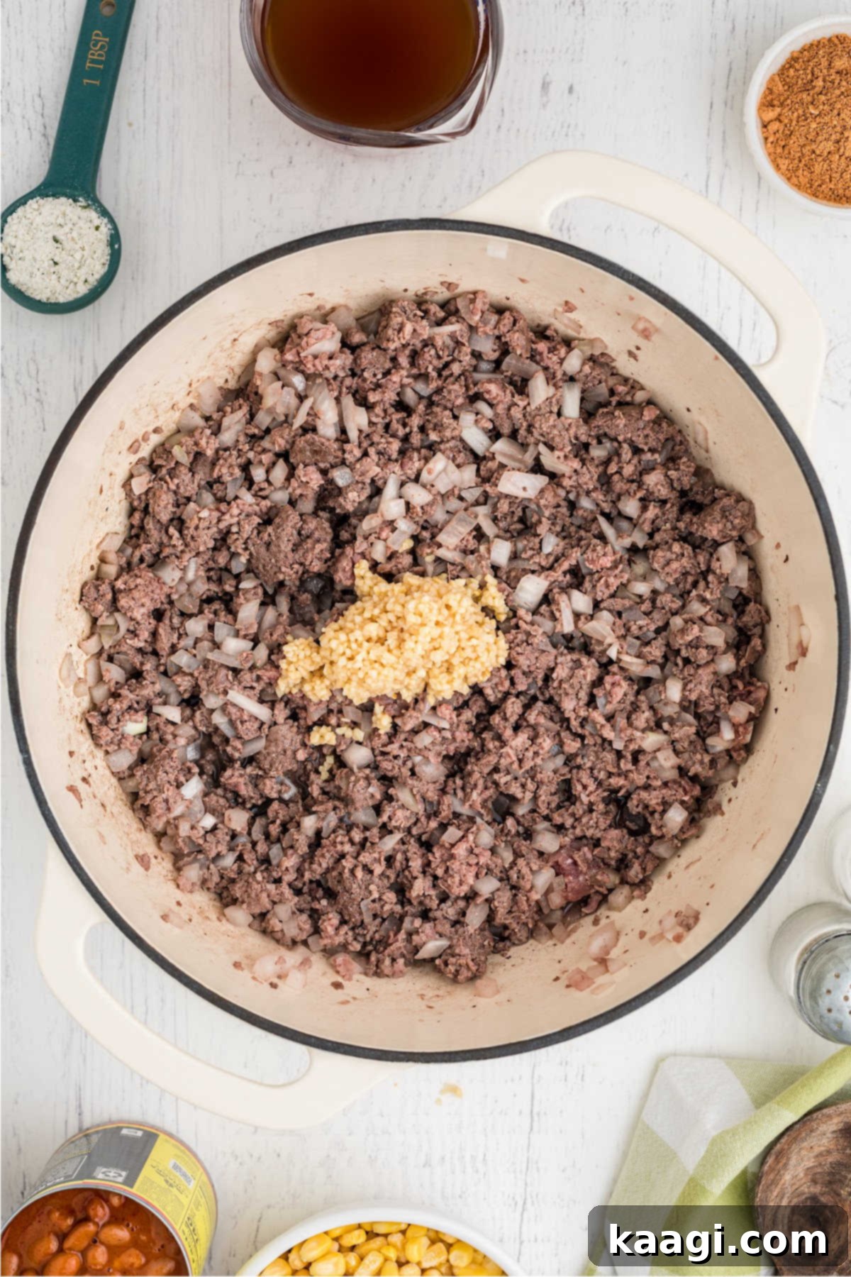 Minced garlic added to a pot of browned ground beef and onions.