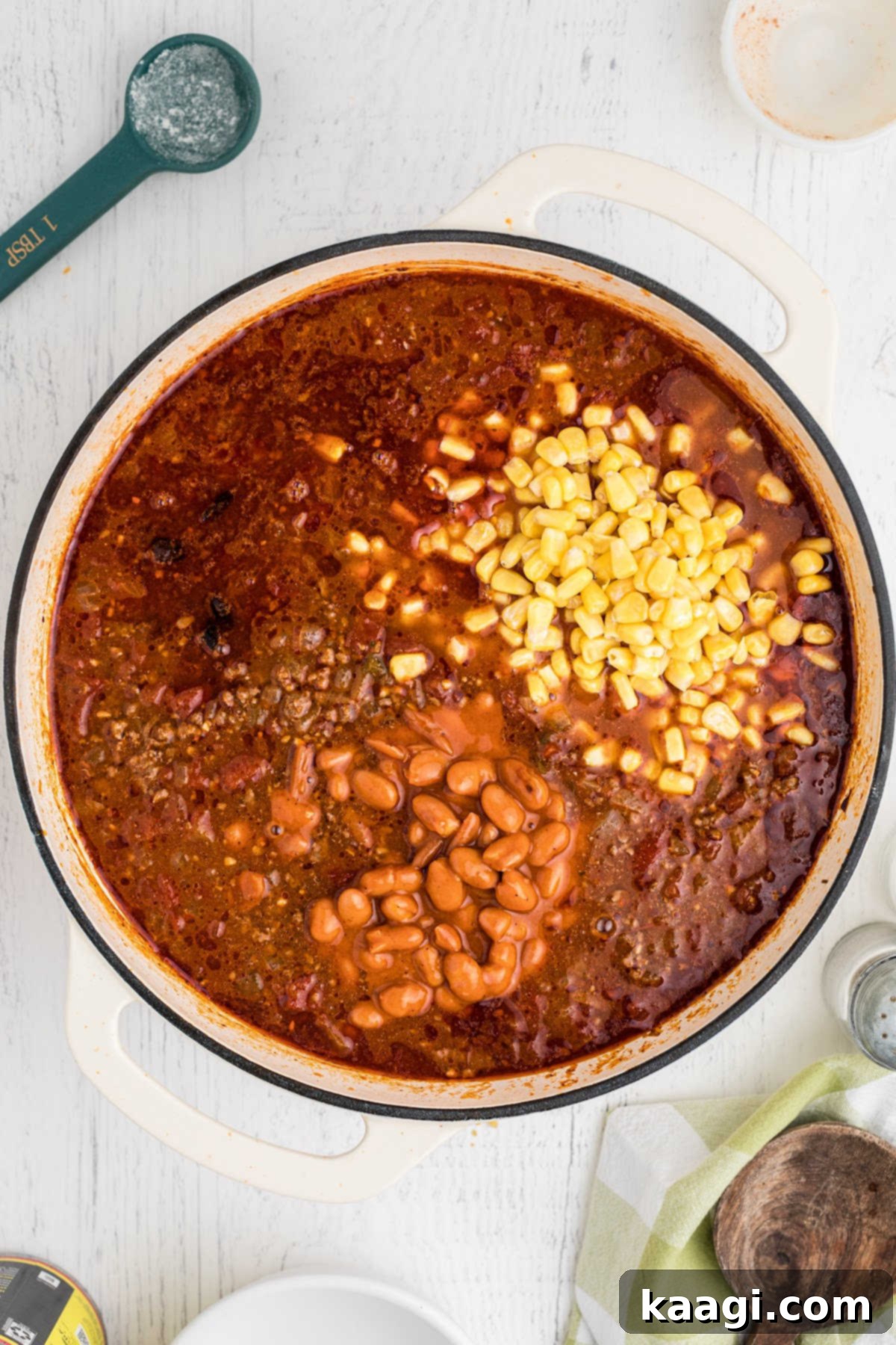 Corn and beans added to a large pot of taco soup ingredients.