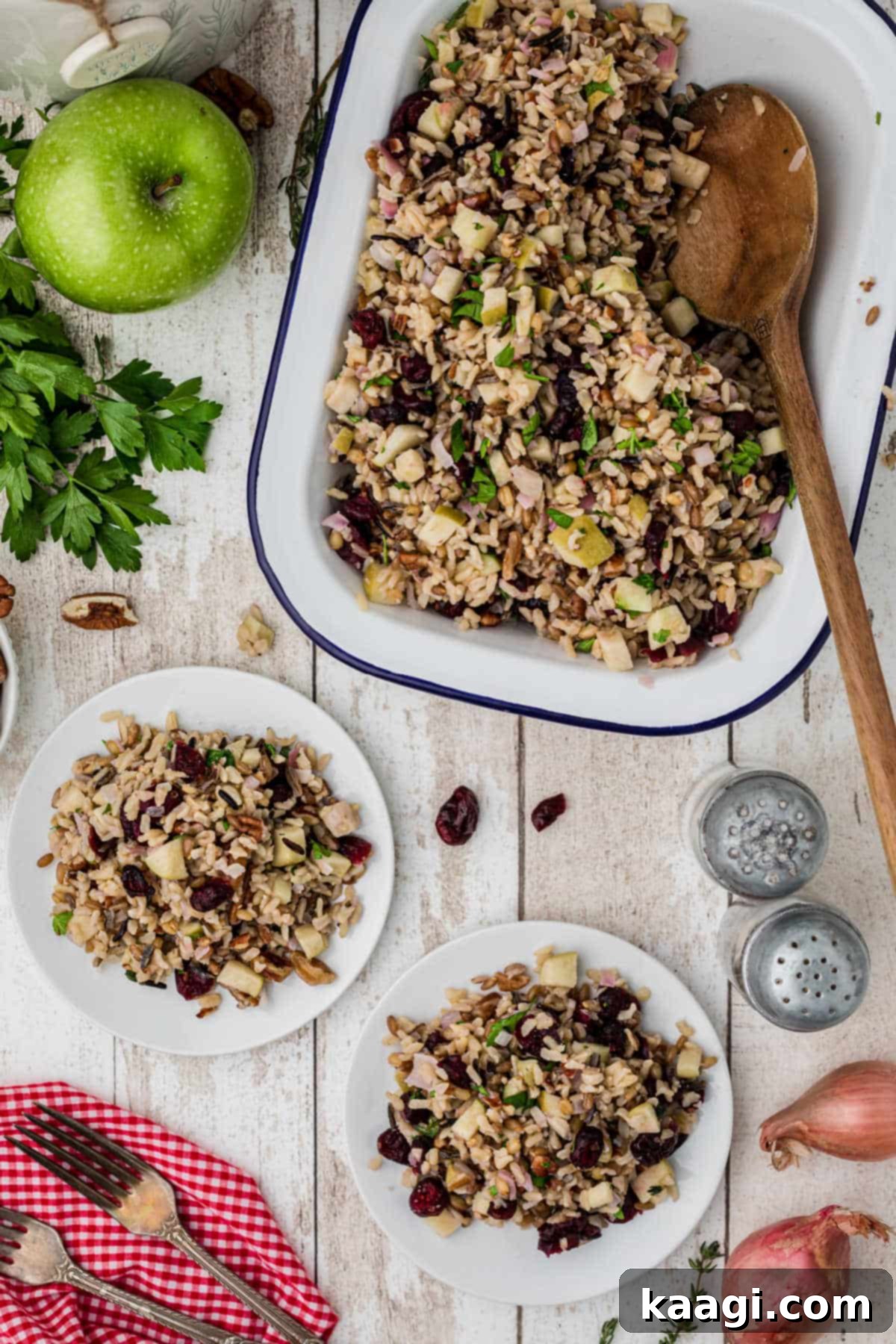 A serving dish filled with cranberry apple rice pilaf, with a serving spoon resting in it, showcasing the rich colors and inviting texture of the finished dish.