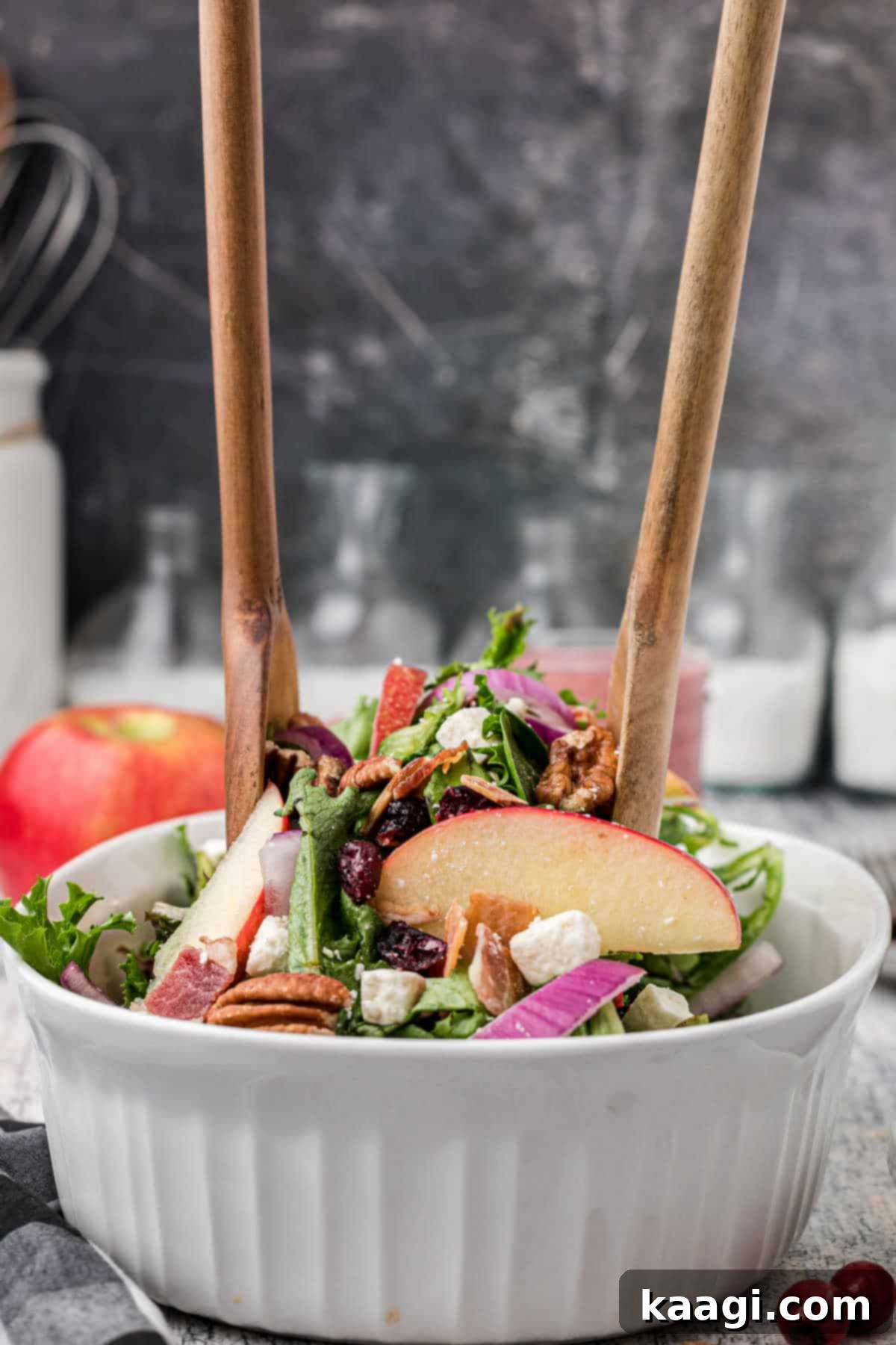 a wooden set of salad fork and spoon digging into a salad bowl