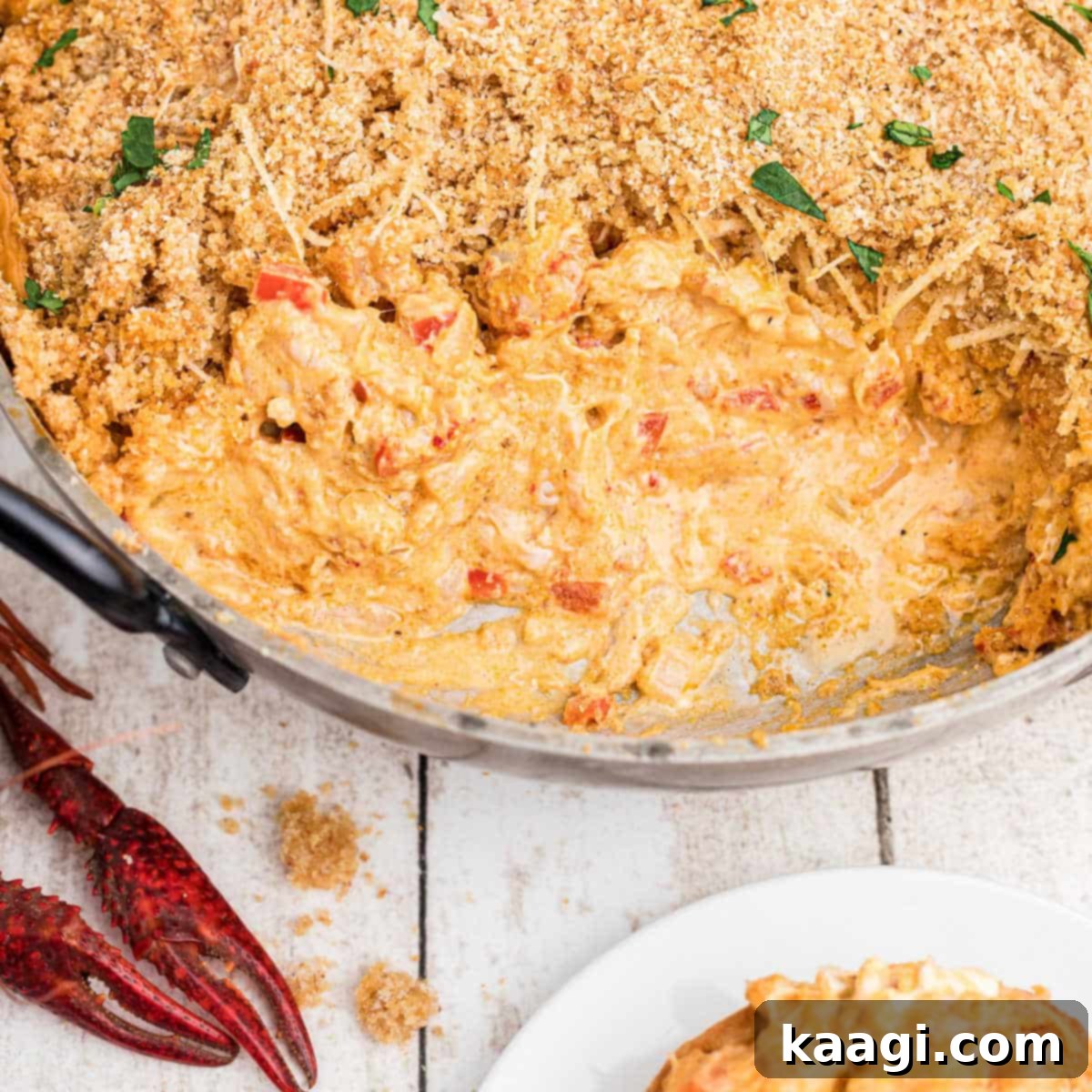 skillet of crawfish dip with breadcrumbs on top, with cream cheese. Crawfish in the corners.