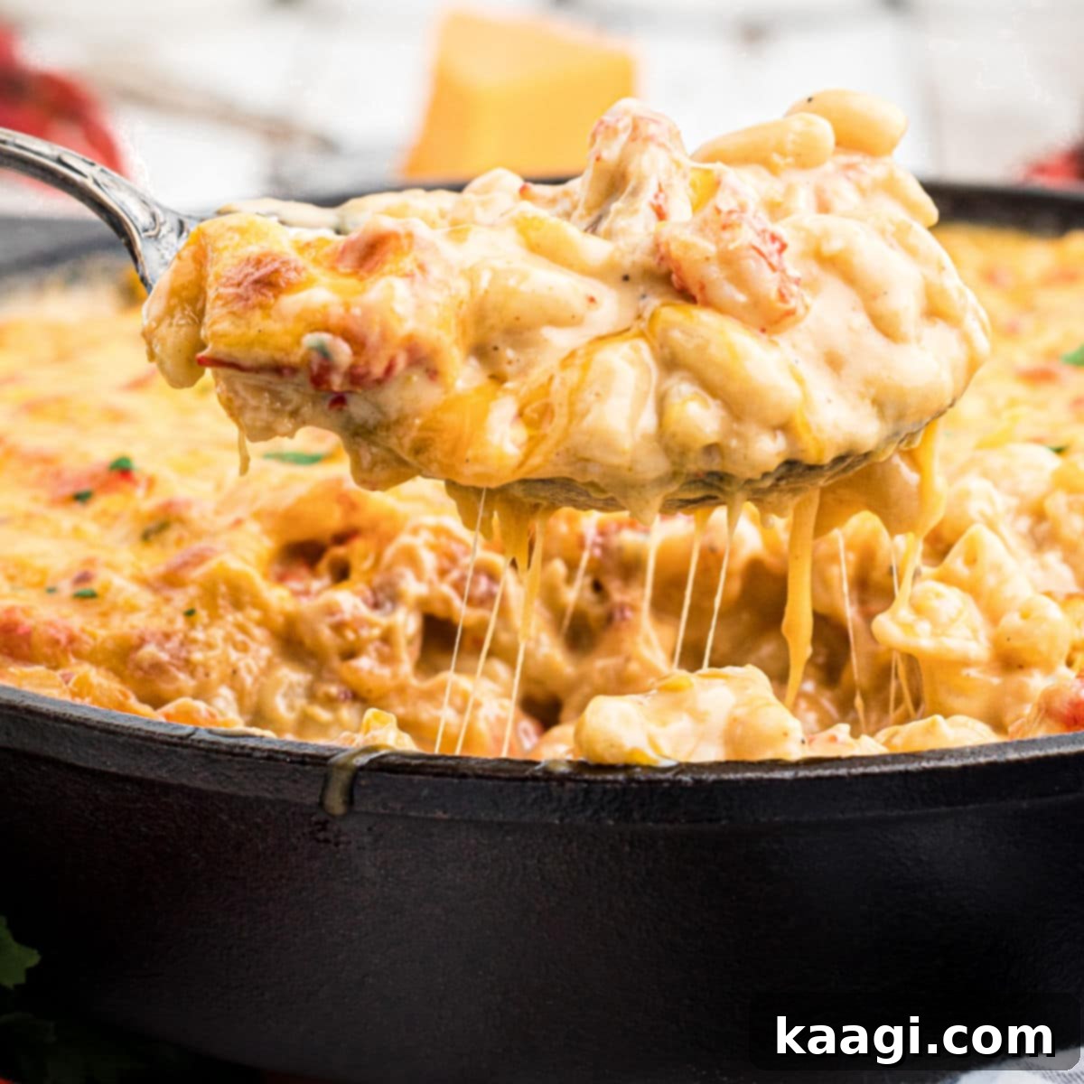 Very close up shot of a spoon lifting out some crawfish mac and cheese from a skillet.