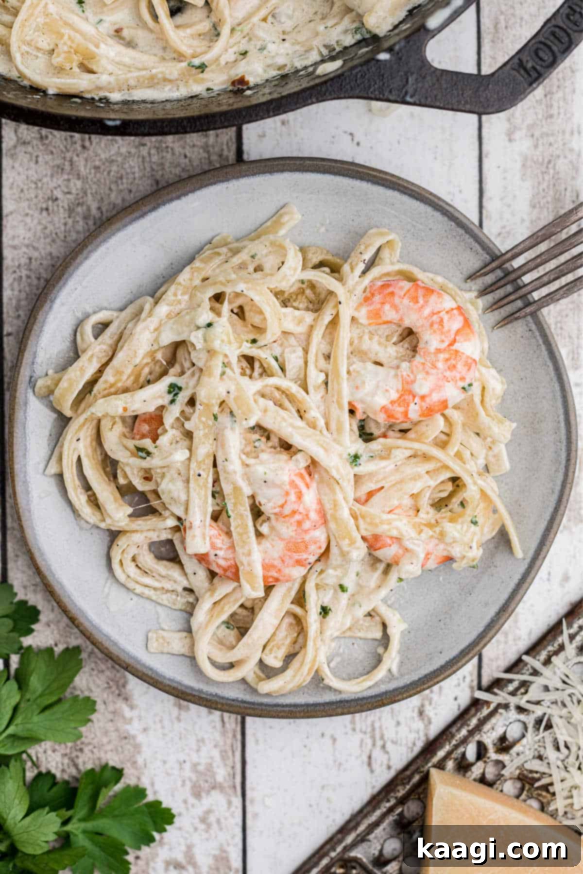 Creamy Garlic Shrimp Pasta Bake 2 Dished out Garlicky Shrimp Alfredo Bake on a plate with a fork on the side, showcasing its creamy texture and golden-brown top.