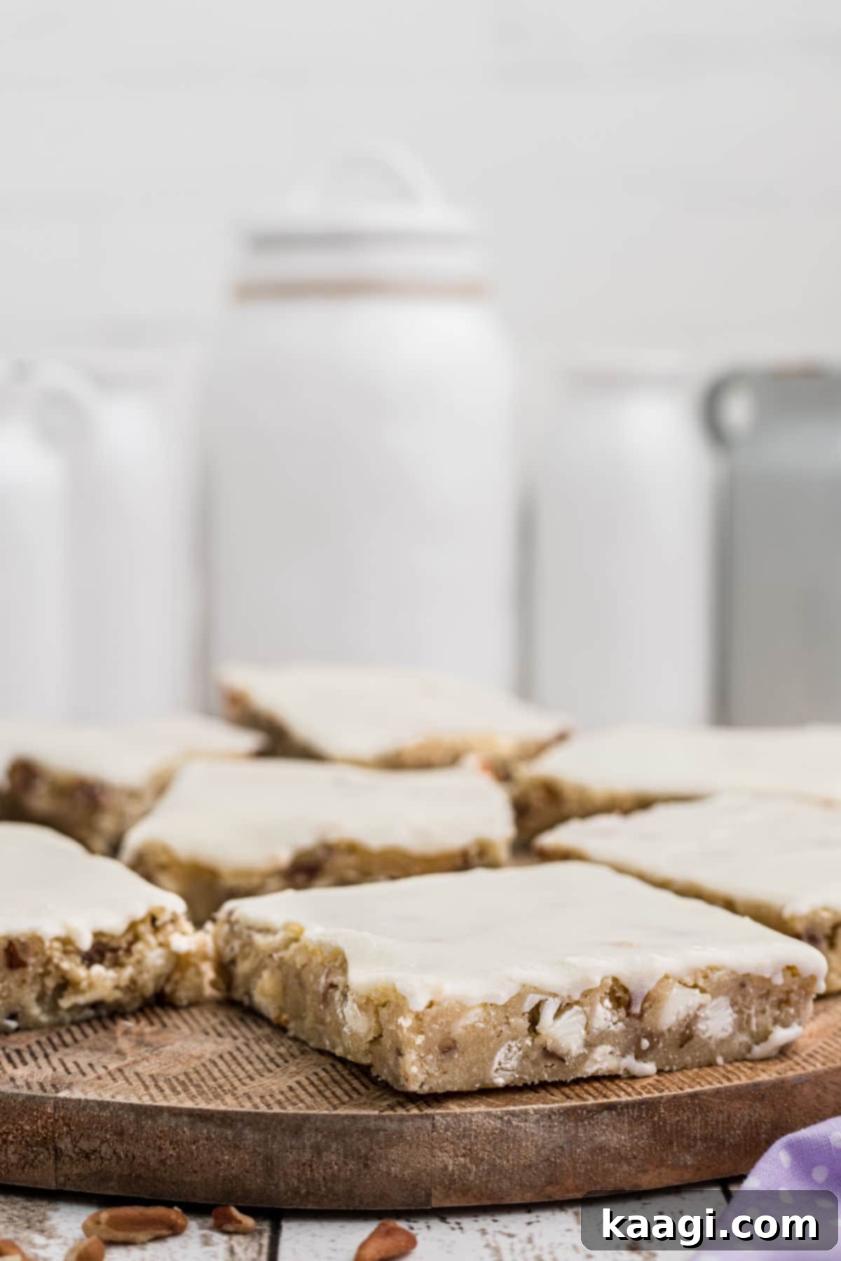 Fudgy vanilla brownies with white chocolate chips and pecans on a wooden board