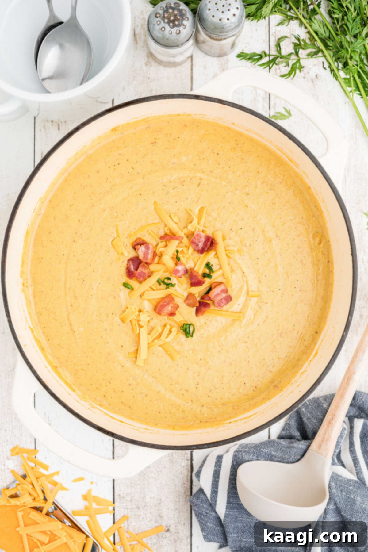 Overhead shot of a large Dutch oven filled with creamy Saltgrass Baked Potato Soup, generously garnished with crispy bacon bits, chopped green onions, and shredded cheddar cheese