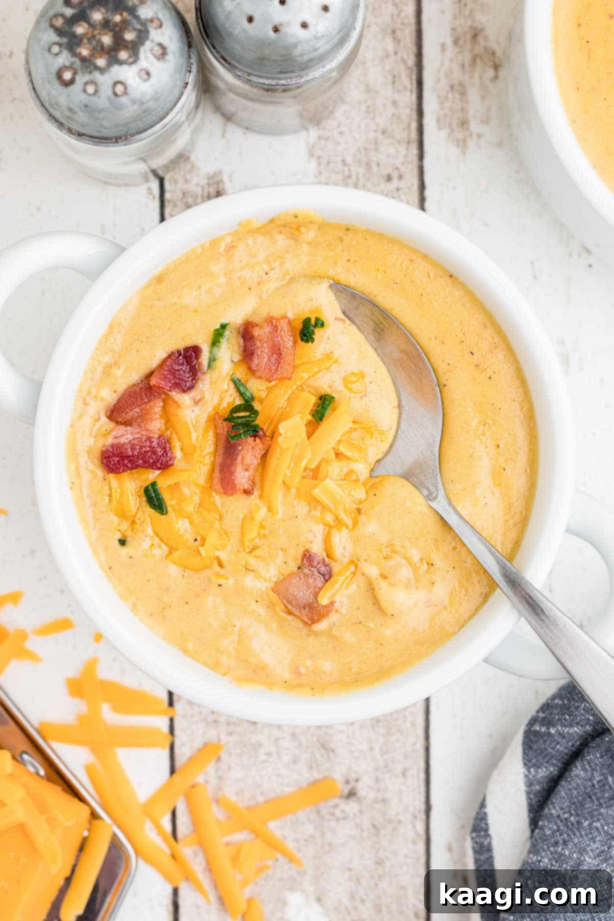 A close-up of a serving bowl filled with creamy Saltgrass Baked Potato Soup, a spoon poised to scoop a delicious portion, emphasizing its inviting texture and warmth.