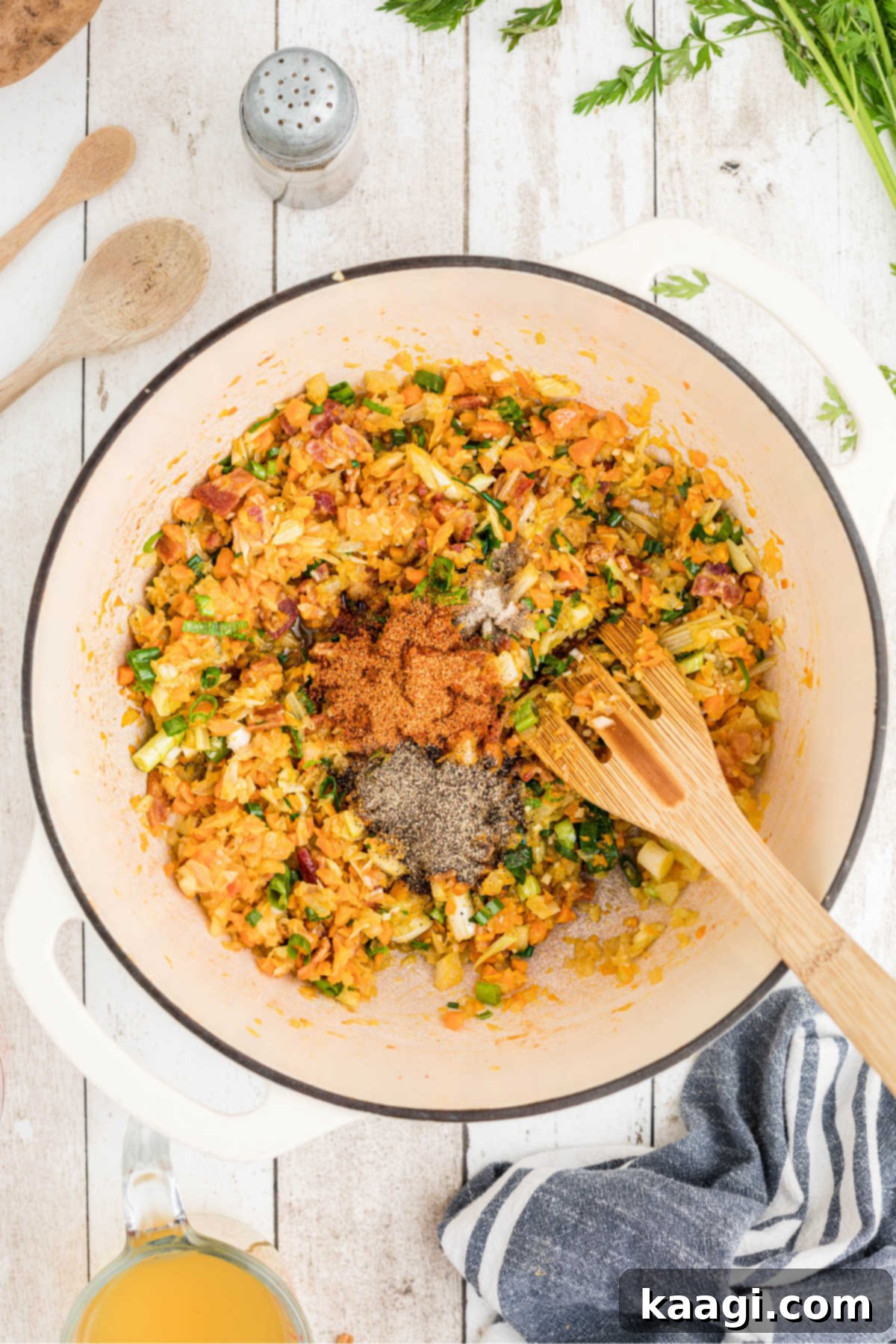 Various seasonings, including Creole seasoning, black pepper, and white pepper, being sprinkled into the large Dutch oven, ready to be mixed into the soup base.