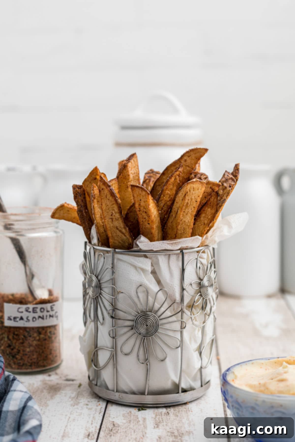 A closeup image of some popeyes cajun fries in a cylindrical flower like container with white paper towel