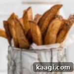 A closeup image of some popeyes cajun fries in a cylindrical flower like container with white paper towel