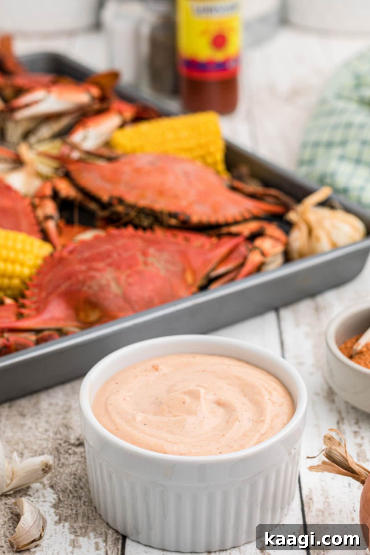 A large bowl of creamy seafood dipping sauce with a side of freshly boiled crabs and lemon wedges