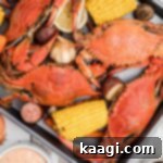 A tray of boiled crabs with veggies and dipping sauce.