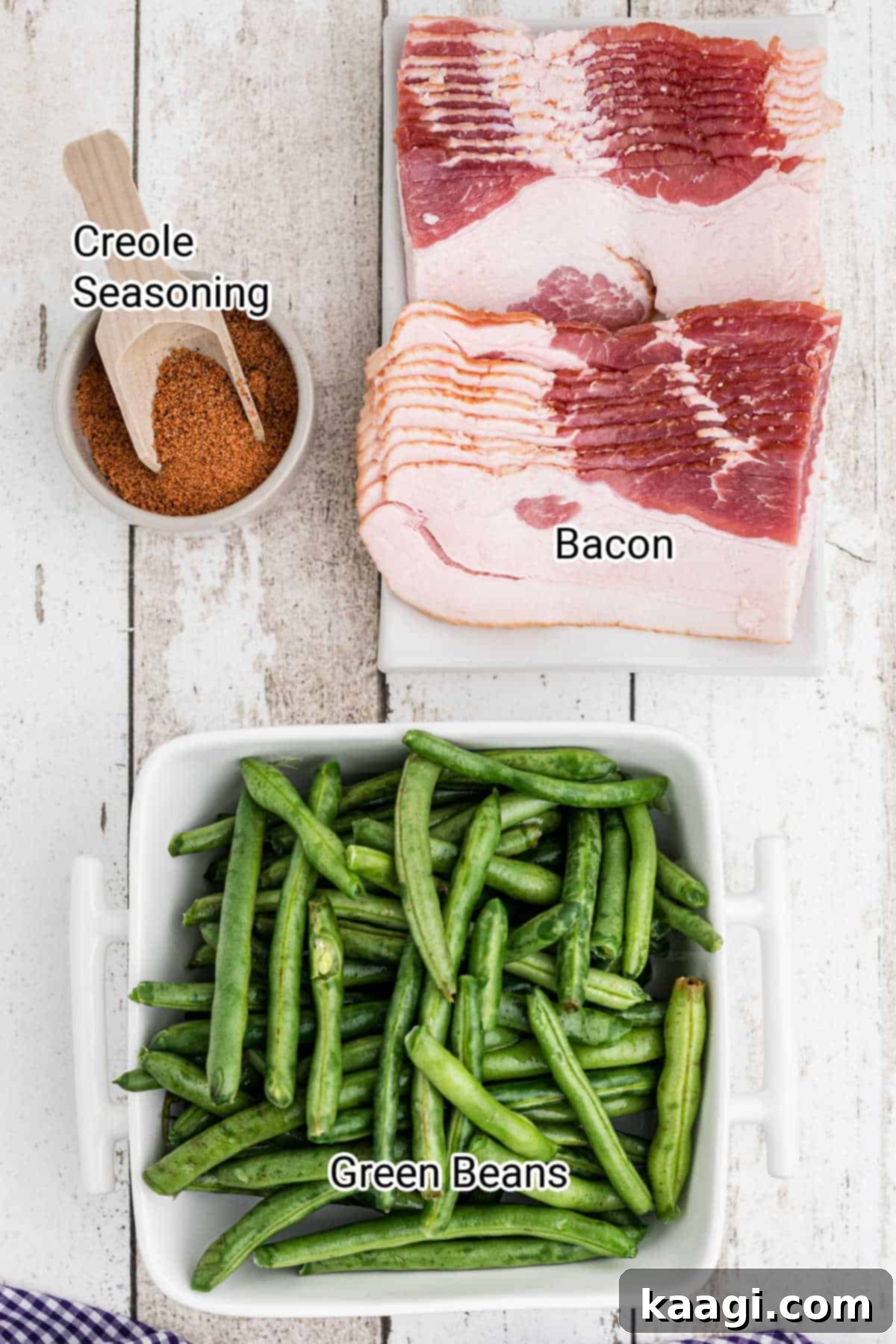 A perfectly arranged display of fresh green beans, strips of bacon, and a jar of Creole seasoning, showcasing the minimal yet essential ingredients for Cajun Green Beans.