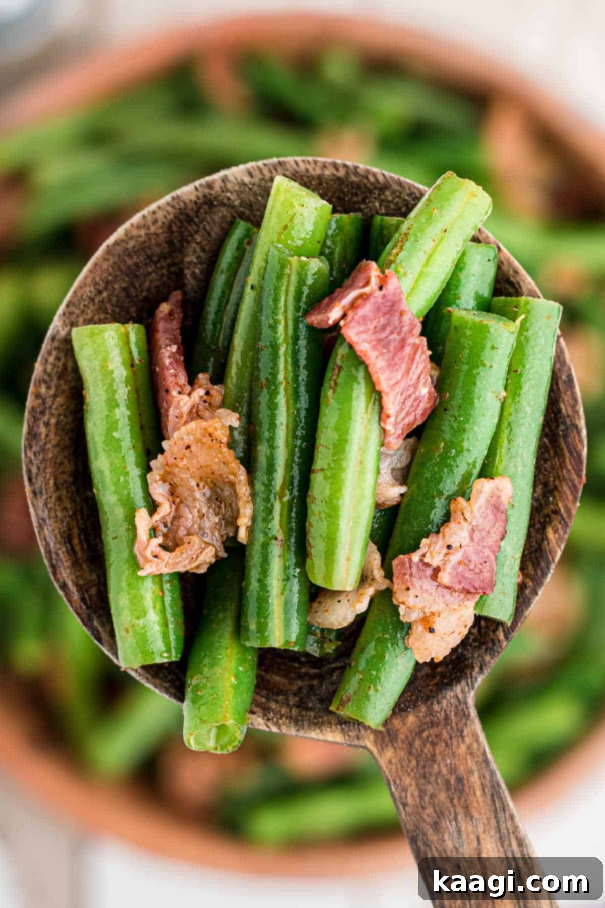A close-up shot of a spoonful of Cajun Green Beans, showcasing the vibrant green beans, crispy bacon pieces, and rich seasoning, ready to be enjoyed.
