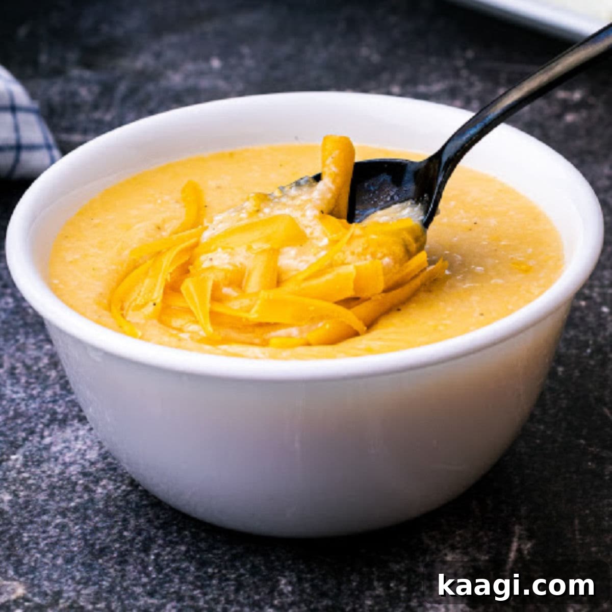 a bowl of cheese grits with grated cheese melting on top with a spoon diving in