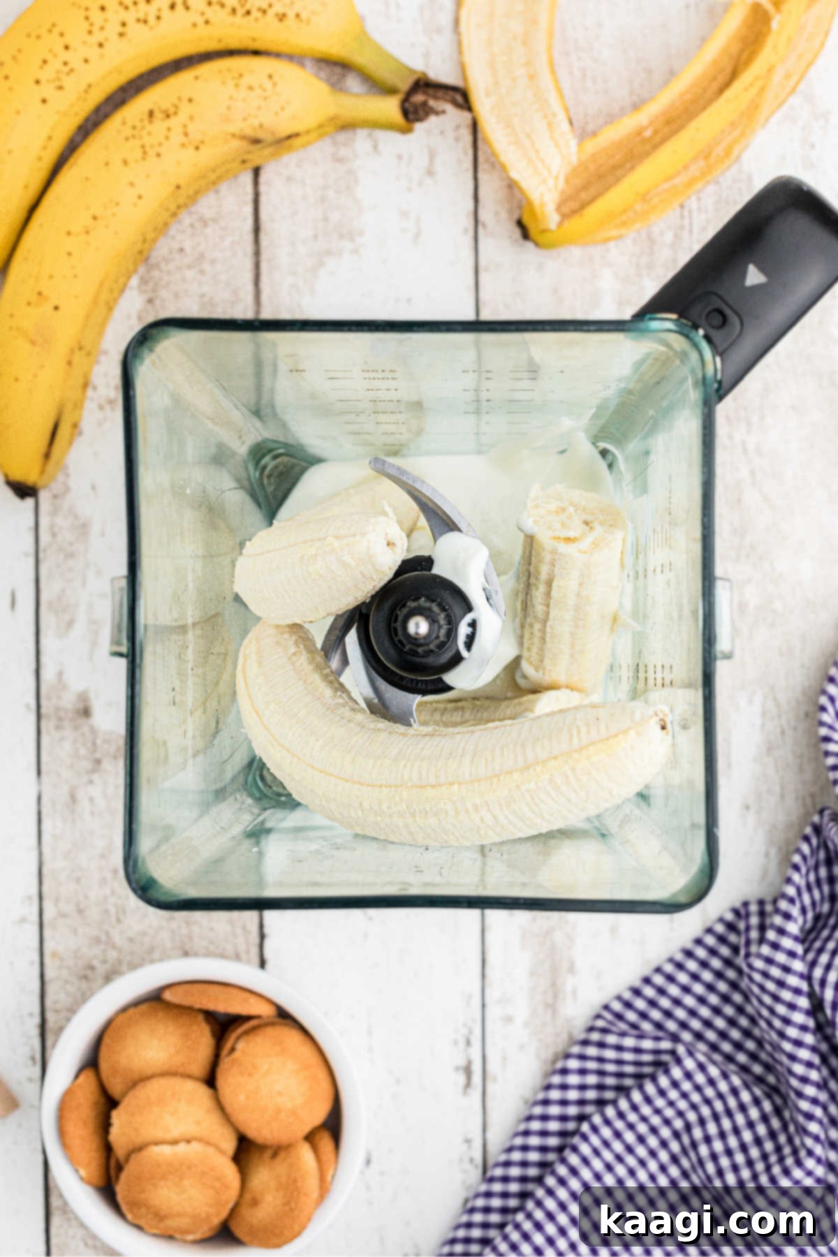 Three ripe bananas being added to a blender, ready to be pureed for the popsicle mixture.