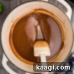 Crafting the Deep Flavor of Dark Roux 10 A spoon stirring a rich, dark roux, ready to be incorporated into a savory dish.