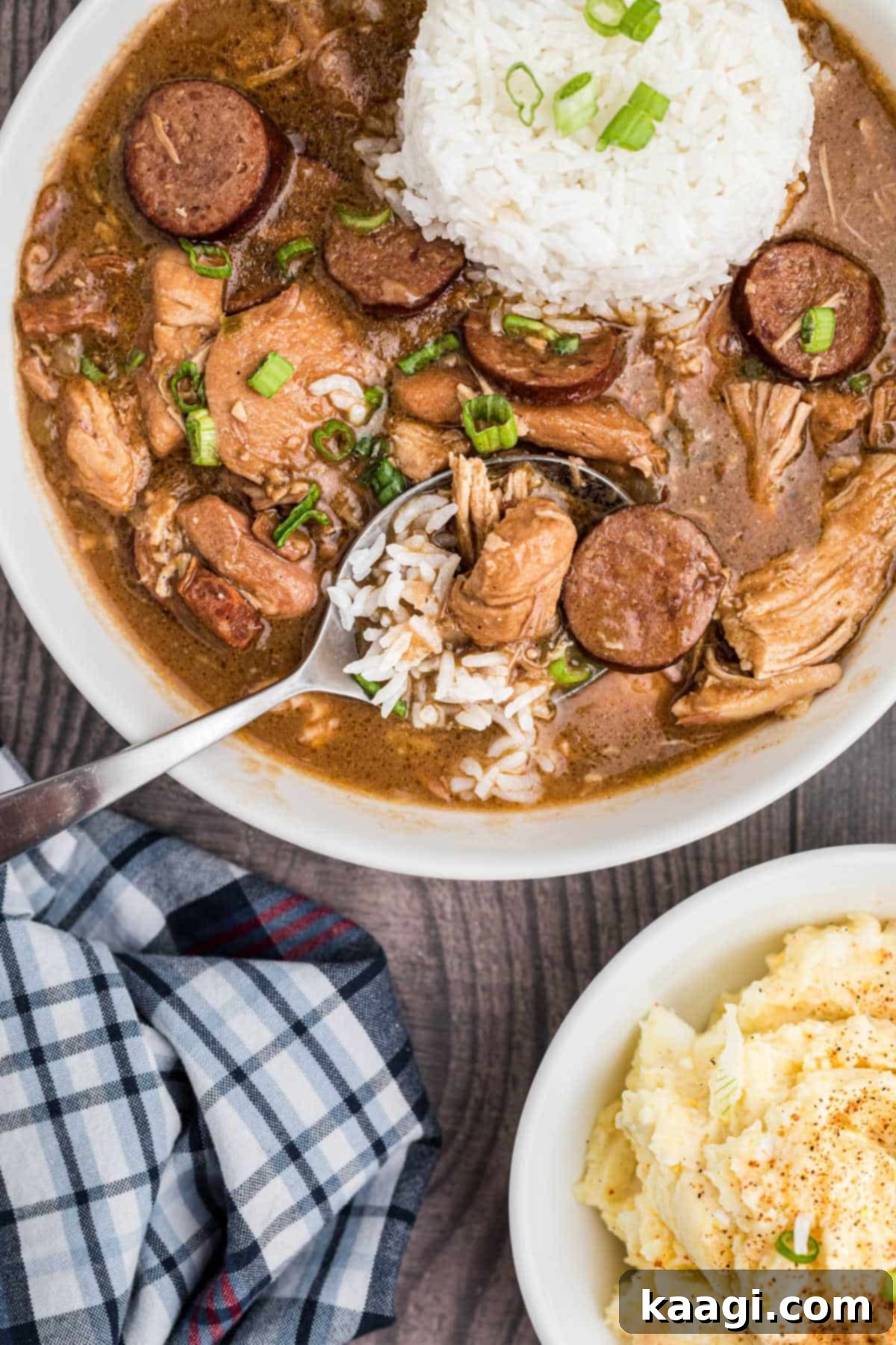 Crafting the Deep Flavor of Dark Roux 8 A hearty bowl of chicken and sausage gumbo, featuring a dark roux, with rice and potato salad on the side.
