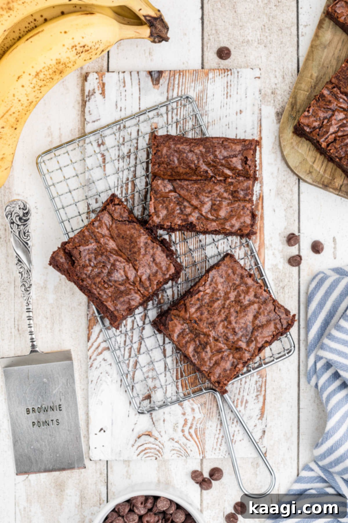 Decadent Banana Brownies 7 An overhead view of three perfectly baked banana brownies resting on a cooling rack, with a few fresh bananas in the background, hinting at the key ingredient.