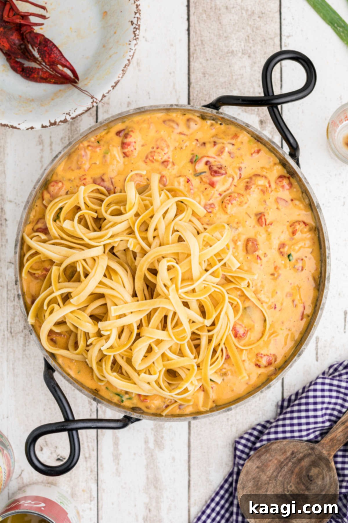 Creamy Cajun Crawfish Fettuccine 11 Cooked fettuccine noodles being added to the crawfish and cheese sauce mixture in a skillet, ready to be tossed.
