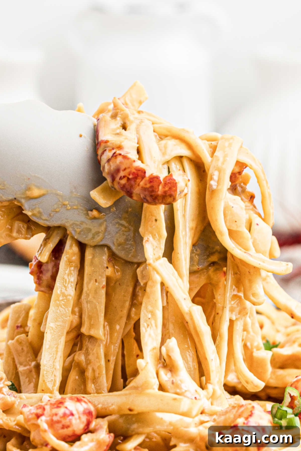 Creamy Cajun Crawfish Fettuccine 12 Very close up view of tongs picking up a generous serving of creamy crawfish fettuccine from a skillet.