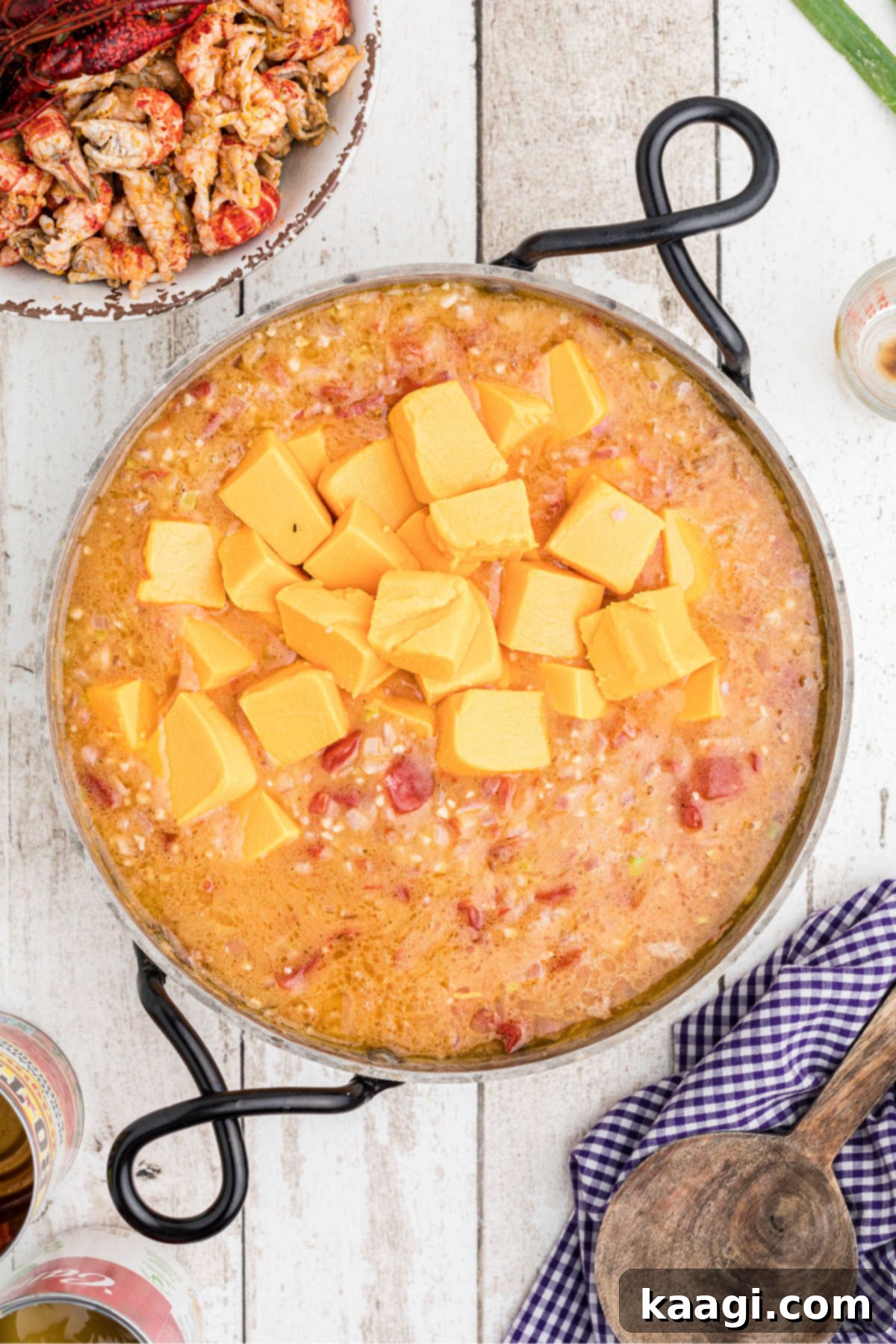 Creamy Cajun Crawfish Fettuccine 9 Cubes of Velveeta cheese being added to the simmering sauce in a skillet, creating a rich cheese sauce.