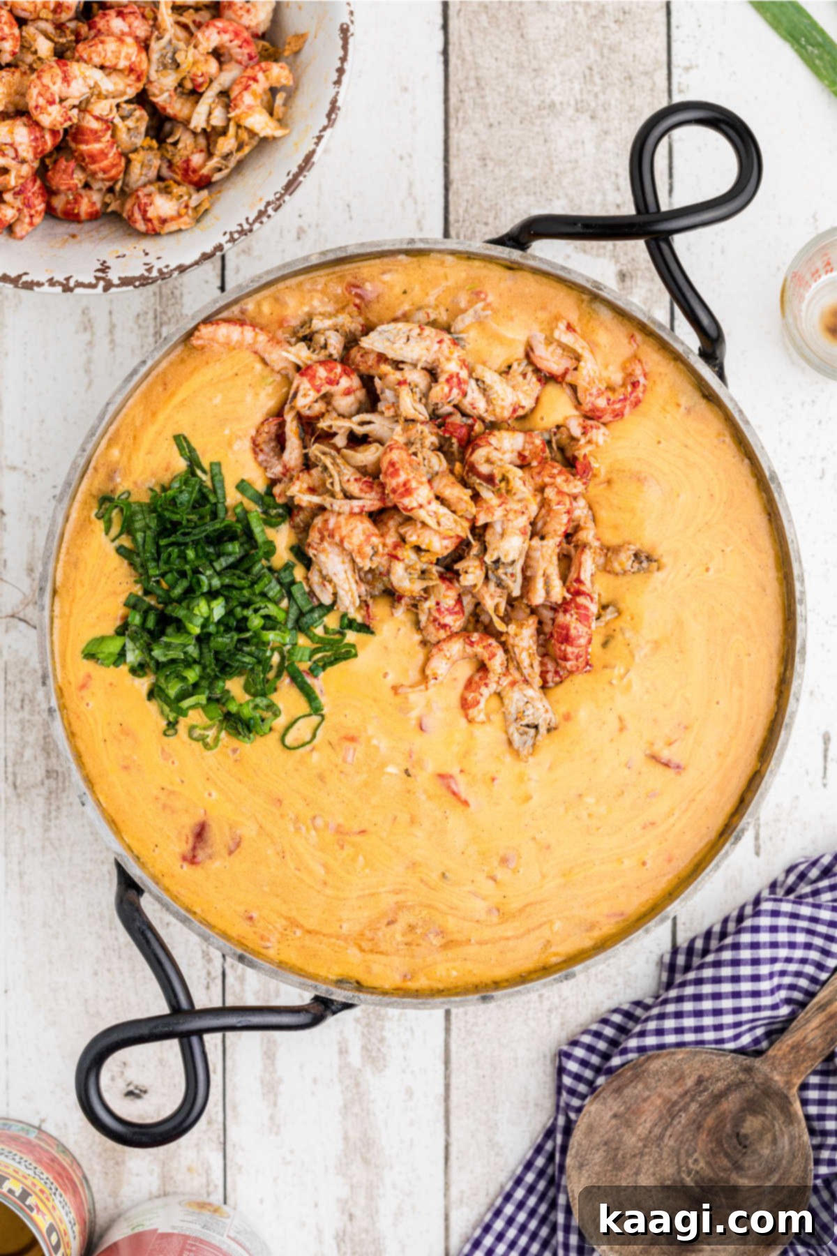 Creamy Cajun Crawfish Fettuccine 10 Crawfish tails and chopped green onions in a skillet with a cheesy sauce.